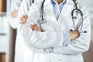 Group of modern doctors standing as a team with arms crossed in hospital office and ready to help patients. Medical help