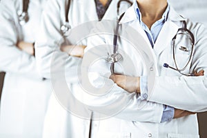 Group of modern doctors standing as a team with arms crossed in hospital office and ready to help patients. Medical help