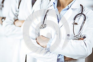 Group of modern doctors standing as a team with arms crossed in hospital office and ready to help patients. Medical help