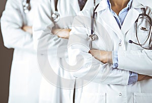 Group of modern doctors standing as a team with arms crossed in hospital office and ready to help patients. Medical help