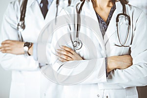 Group of modern doctors standing as a team with arms crossed in hospital office and ready to help patients. Medical help