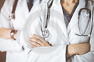 Group of modern doctors standing as a team with arms crossed in sunny hospital and ready to help patients. Medical help