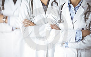 Group of modern doctors standing as a team with arms crossed in sunny hospital and ready to help patients. Medical help