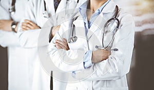 Group of modern doctors standing as a team with arms crossed in sunny hospital and ready to help patients. Medical help