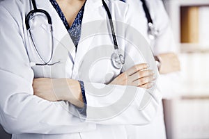 Group of modern doctors standing as a team with arms crossed in sunny hospital and ready to help patients. Medical help