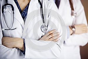 Group of modern doctors standing as a team with arms crossed in sunny hospital and ready to help patients. Medical help