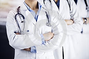 Group of modern doctors standing as a team with arms crossed in sunny hospital and ready to help patients. Medical help