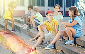 Positive tweenagers friendly blabbing while sitting on steps outdoors photo