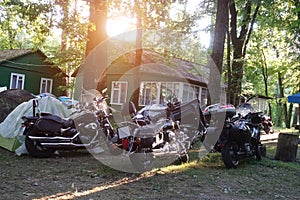 Group of motorbikes parked near a wooden house in the forest