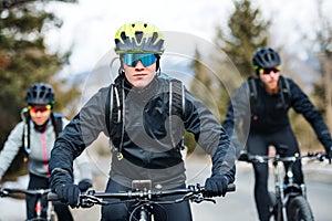 Group of mountain bikers riding on road outdoors in winter.
