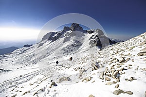 Group of mountaineers walking through a landscape full of snow and rocks on a morning in the mountains of Mexico