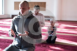 Group of muliethnic religious muslim young people  praying an dreading Koran together. Group of muslims praying in the mosque