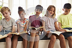 Group Of Multi-Cultural Children Reading On Window Seat