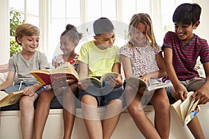 Group Of Multi-Cultural Children Reading On Window Seat photo