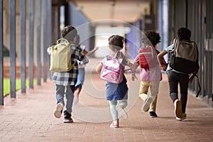 Group Of Multi-Cultural Elementary School Pupils Running Along Walkway Outdoors At School