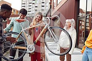 Group Of Multi-Cultural Friends On City Street Lifting Sustainable Bamboo Bicycle