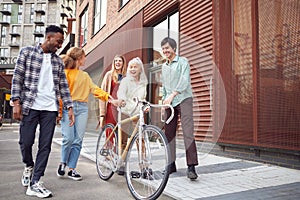 Group Of Multi-Cultural Friends Walking On City Street With Sustainable Bamboo Bicycle