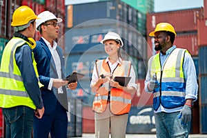 Group of multi ethnic cargo contianer workers stand and discuss together about the project  with happiness and stack of tank as