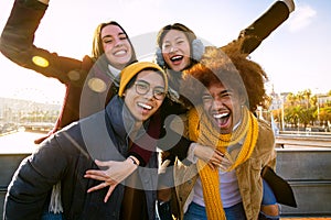 Group of multi-ethnic cheerful happy friends smiling at camera having fun outdoors. Boys carrying girls on back.