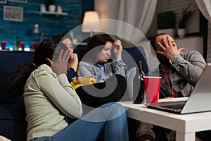 Group of multi-ethnic friends watching horror thriller movie on laptop computer