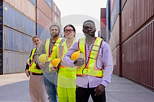 Group of multi ethnic team of engineers and workers standing together with containers in shipping cargo yard