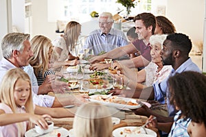 Group Of Multi-Generation Family And Friends Sitting Around Table And Enjoying Meal photo