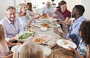 Group Of Multi-Generation Family And Friends Sitting Around Table And Enjoying Meal photo