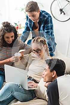 group of multicultural teens looking at laptop
