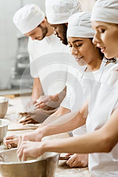 group of multiethnic bakers kneading