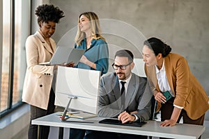 Group of multiethnic business people analyzing data using computer while working in the office