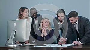 Group of multiethnic diverse young business people in a meeting standing around a table with serious expressions