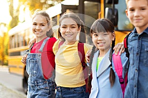 Group Of Multiethnic Happy Kids Standing Outdoors Near School Bus
