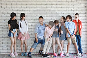 Group of multiethnic school kids playing together in line in classroom with happy smiling face on white wall background education