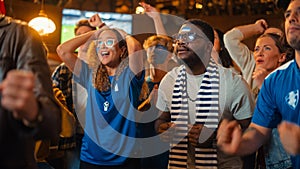 Group of Multiethnic Soccer Fans with Colored Faces Watching a Live Football Match in a Sports Bar