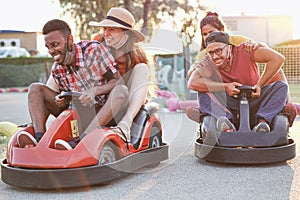 Group of multietnic friends having fun with go kart  - Young people with face mask on smiling and cheerful at mini car racing -