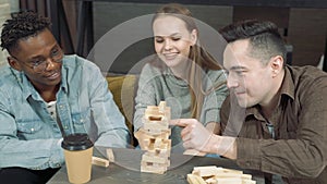 Group of multinational friends playing block removal game in the living room at home