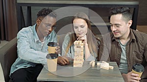 Group of multinational friends playing block removal game in the living room at home.Friendship, leisure and entertainment concept