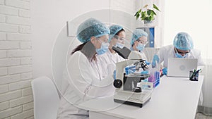 A group of multinational laboratory technicians, an African American female laboratory assistant conducts research under