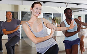 Group of multinational smiling adult people enjoying active dance movement