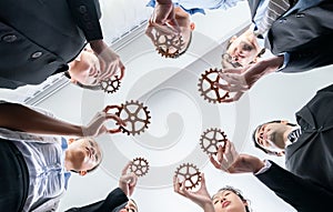 Group of multiracial business people joining gear wheels together. Habiliment