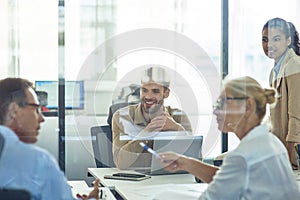 Group of multiracial business people sitting in board room in the modern office and discussing something while having a