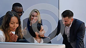 Group of multiracial business team shoked with result, surprised, smiling and looking at laptop computer photo