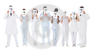 Group Of Multiracial Doctors Hiding Behind Question Mark Sign