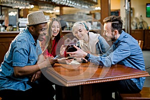 Group of multiracial friends enjoying in cafe together. Young people meeting in a cafe. Young men and women sitting at