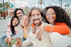 Group of multiracial friends smiling and taking a selfie portrait. Young people having fun on a social gathering. Joyful