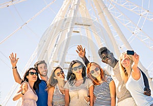 Group of multiracial happy friends taking selfie at ferris wheel