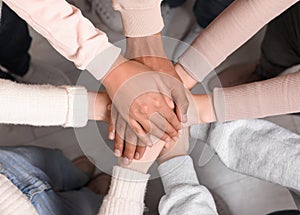 Group of multiracial people joining hands together indoors, top view