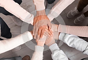 Group of multiracial people joining hands together indoors, top view