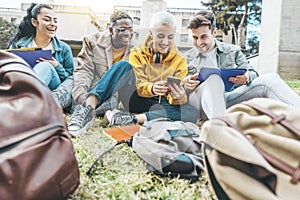 Group of multiracial students having fun sitting in college campus together - Happy teenagers using smart mobile phone outside