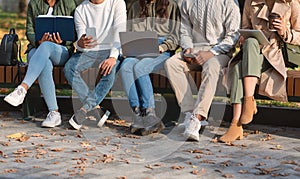 Group of students sitting on bench in park and studying